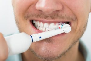 Человек чистит зубы электрической щеткой